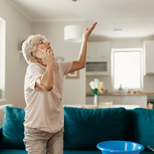 Homeowner calling Roofing Guys Gold Coast for urgent roof leak detection after spotting a ceiling leak in her home.