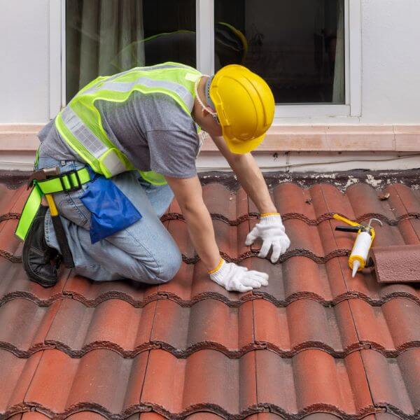 Roofer from Roofing Guys Gold Coast replacing damaged roof tiles during a full tile roof replacement on a residential property.