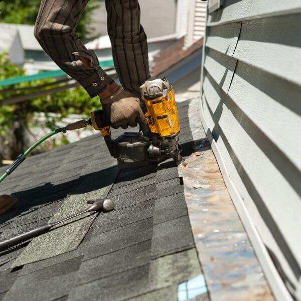 Roofer from Roofing Guys Gold Coast using nail gun to carry out emergency roof repairs on a storm-damaged roof.