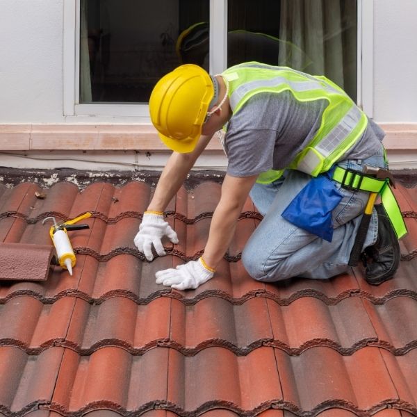 Roofing Guys Gold Coast roofer repairing terracotta tiles during a roof restoration to stop leaks and improve appearance.