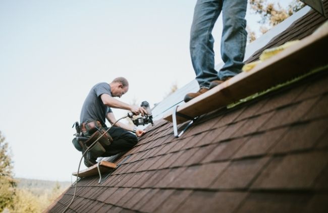 Roofing Guys Gold Coast team carrying out roof restoration on a shingle roof, securing new materials for long-term durability.